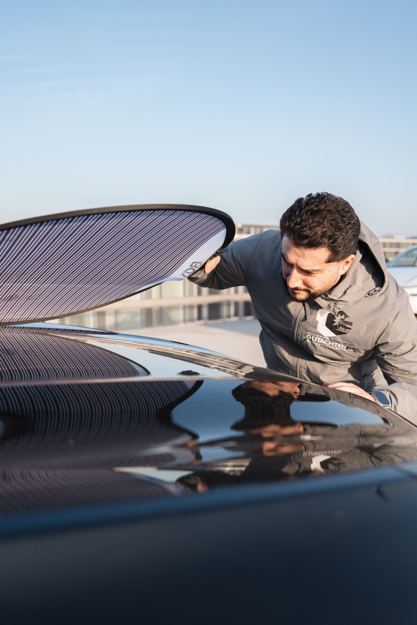 Halis Kaya prüft den Lack einer Motorhaube mit einer Streifentafel
